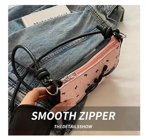 Detail showing the smooth silver metal zipper on the pink bow print shoulder bag