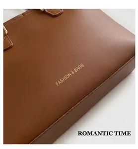 Close-up of brown pebbled leather tote bag with gold-stamped Fashion & Bags logo lettering