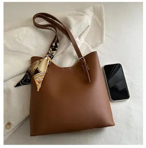 Detail view of large dark brown tote bag with silk scarf next to a mobile phone