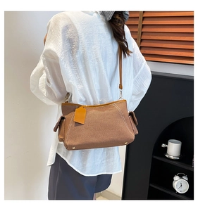 Side view of large brown woven tote bag with leather straps and side pockets on a model
