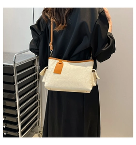 Detail of adjustable leather strap and side pockets on a canvas crossbody bag