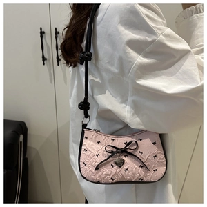 Détail du sac à bandoulière froncé rose avec nœud noir et pendentif en forme de cœur