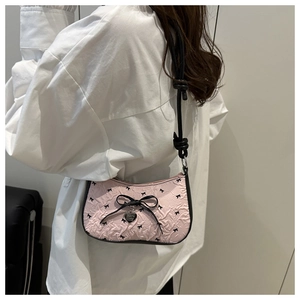 Close-up of pink ruched shoulder bag featuring black bows and silver heart charm detail