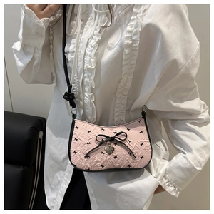 Détail du sac à bandoulière rose avec broderies de nœuds noirs et pendentif cœur