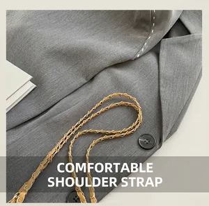 Close-up of golden braided chain strap and black button on grey textured fabric