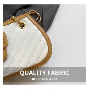 Close-up of quilted white leather shoulder bag with brown piping and gold chain