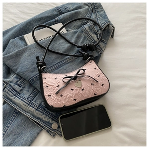 Détail du sac rose texture bulles avec broderie nœud noir et pendentif cœur en métal