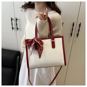 Dettaglio borsa tote bicolore effetto serpente con foulard decorativo in seta a cuori