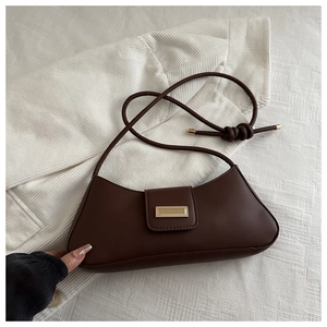 Detail of dark brown baguette bag with gold buckle on corduroy fabric background