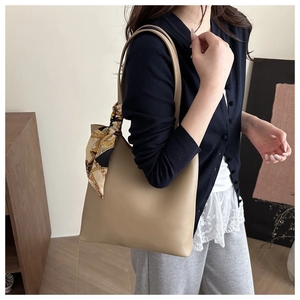 Detail of khaki tote bag with silk scarf accessory and minimalist leather texture