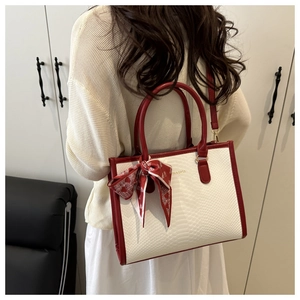 Détail du sac cabas à motif serpent avec anses rouges et foulard décoratif en soie