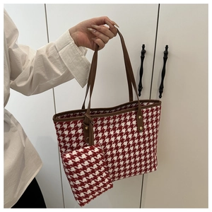 Detalle del bolso tote de cuadros rojos y blancos con asas de cuero y monedero a juego