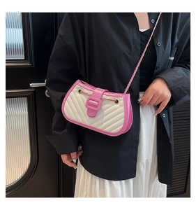 Detail shot of a pink and white quilted crossbody bag with golden chain strap on a model