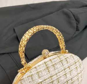 Detail of elegant woven tweed bag featuring a golden metal handle and rhinestone ball clasp