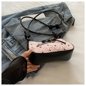 Détail du sac à main plissé rose avec broderie de nœuds noirs et contraste chic