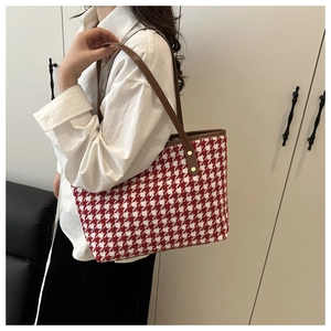 Detalle del bolso tote de pata de gallo con correas de cuero y remaches dorados
