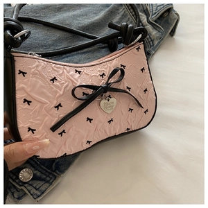 Détail du sac rose à imprimé nœuds avec nœud en cuir noir et pendentif cœur en métal