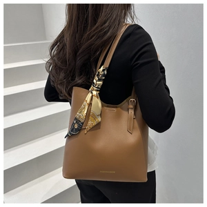 Detail of brown tote bag featuring silk scarf handle and FASHION & BAGS branding
