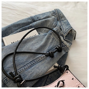 Détail du sac en cuir gaufré rose avec bandoulière à nœud noir et motif étoilé
