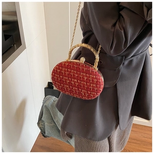 Close-up of red and gold tweed clutch with crystal buckle and metal top handle