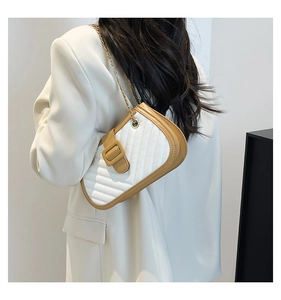 Detailed view of quilted leather handbag with gold chain strap on white blazer