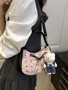 Pink pleated handbag with black bow prints and a white bear plush charm accessory