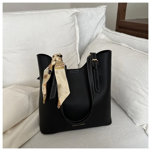 Close-up of black tote bag featuring white contrast stitching and printed silk scarf detail