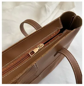 Detail shot of the smooth gold metal zipper and woven texture on a brown tote bag