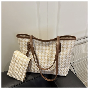 Detalle del bolso tote de paja tejida con estampado de pata de gallo y cuero marrón