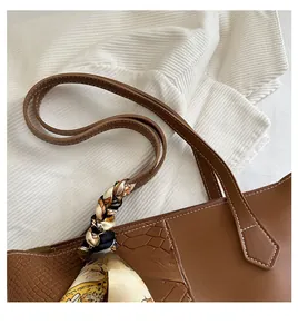 Detail of caramel brown tote bag showing crocodile texture stitching and silk scarf wrap