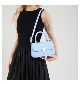 Detail of light blue saddle bag with golden metal buckle and smooth PU leather texture