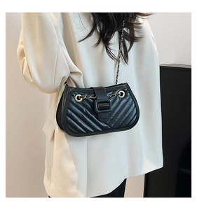 Detail of black V-stitch quilted shoulder bag with gold chain strap and large buckle