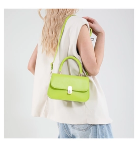 Neon green crossbody bag shown on model featuring a metallic clasp and slender strap