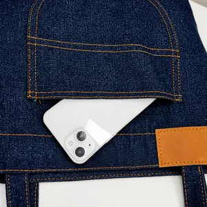 Detalle del bolsillo frontal de un bolso de mezclilla azul con un smartphone