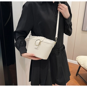 Detail of cream woven crossbody bag with elegant gold horseshoe metal buckle