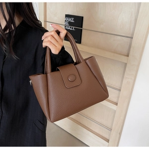 Detailaufnahme der dunkelbraunen Handtasche aus Leder mit Litschi-Maserung und Klappverschluss