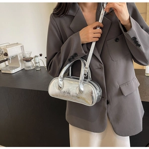 Detail of silver metallic handbag showing crinkled texture and branding on the surface