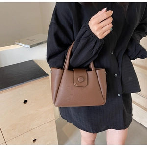 Detailed close-up of dark brown lychee-pattern leather texture and round decorative clasp