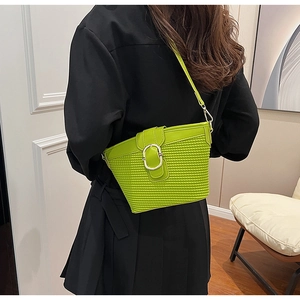 Detail of bright green woven texture underarm bag with round metal buckle on shoulder