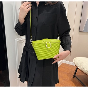 Detail of neon green woven bucket bag featuring silver metal buckle and adjustable strap