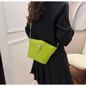 Green leather bucket bag with woven texture and silver buckle worn on a model's back