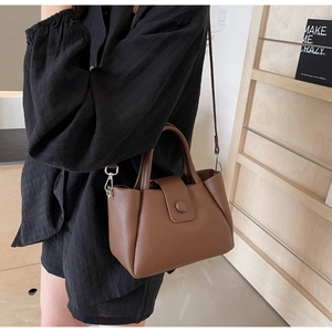 Detail of a brown lychee pattern leather bucket bag with silver hardware and shoulder strap