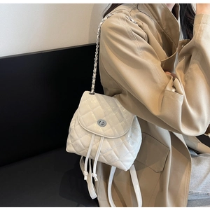 Detail des weißen gesteppten Mini-Rucksacks mit glänzender Lederstruktur und Metallkettenriemen