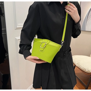 Detail of neon green PU bag with textured surface and silver metal clasp on black outfit