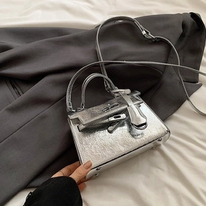 Chic metallic silver mini handbag with pleated texture and top handle in a lifestyle setting