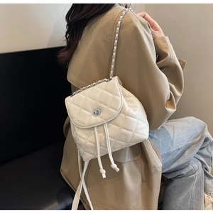 Detail eines weißen Stepp-Minirucksacks mit silbernen Kettenriemen und Drehverschluss