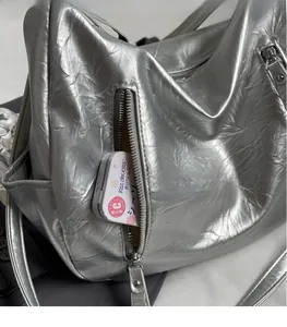 Detailed macro view of silver metallic tote bag with functional zipper pockets and textures