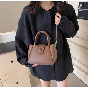 Vue détaillée du sac seau en cuir marron grainé avec poignée et finitions métalliques