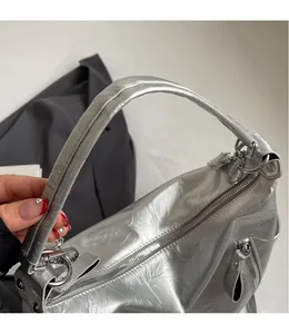 Close-up of silver crescent bag with metallic pleats and smooth shoulder strap