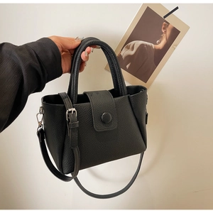 Détail d'un sac à main en cuir grainé noir avec boucle ronde et poignée supérieure